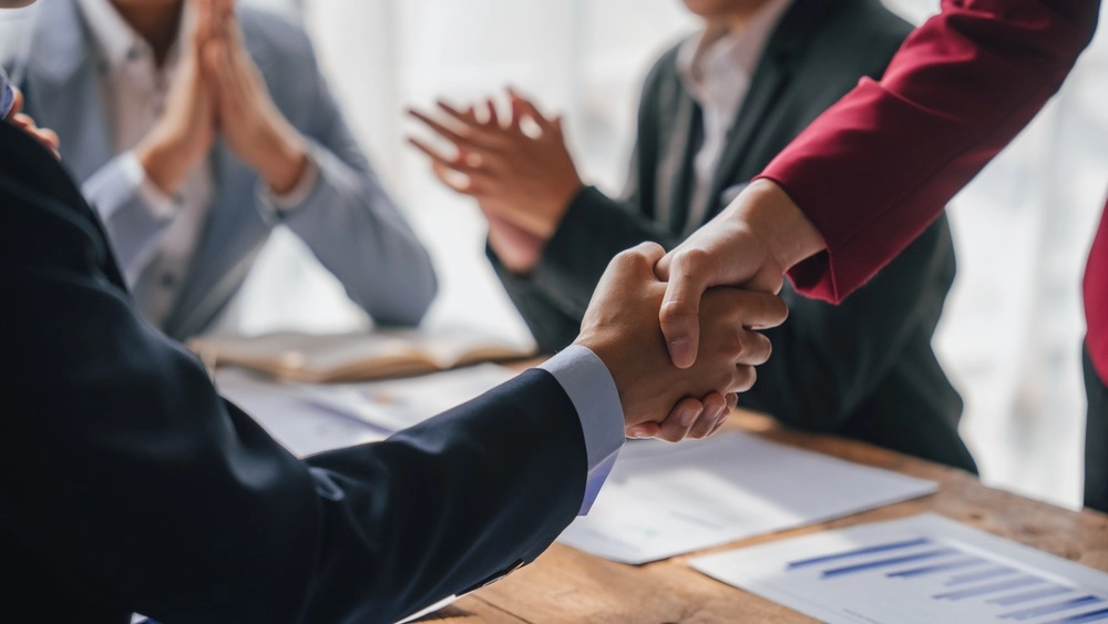 Shaking hands, Team of lawyers and tax auditors brainstorming together and calculating the balance sheet and historical financial accounts of the company and shareholders.