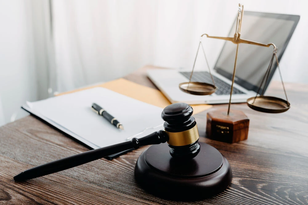 Business and lawyers discussing contract papers with brass scale on desk in office.