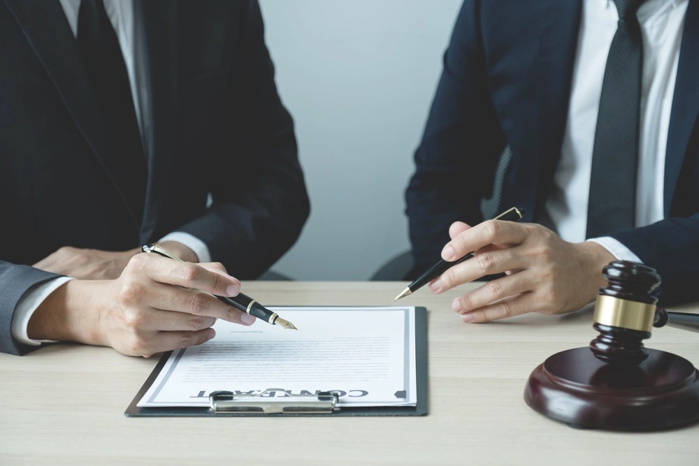 Lawyer hand holding pen and providing legal consult business dispute service to the man at the office with justice scale and gavel hammer.