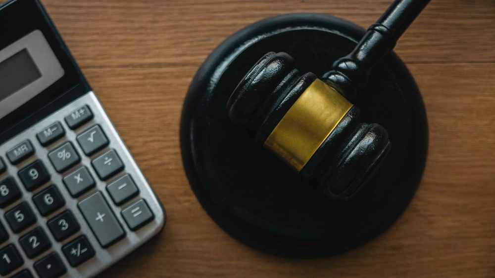 Gavel and calculator on a wooden background.